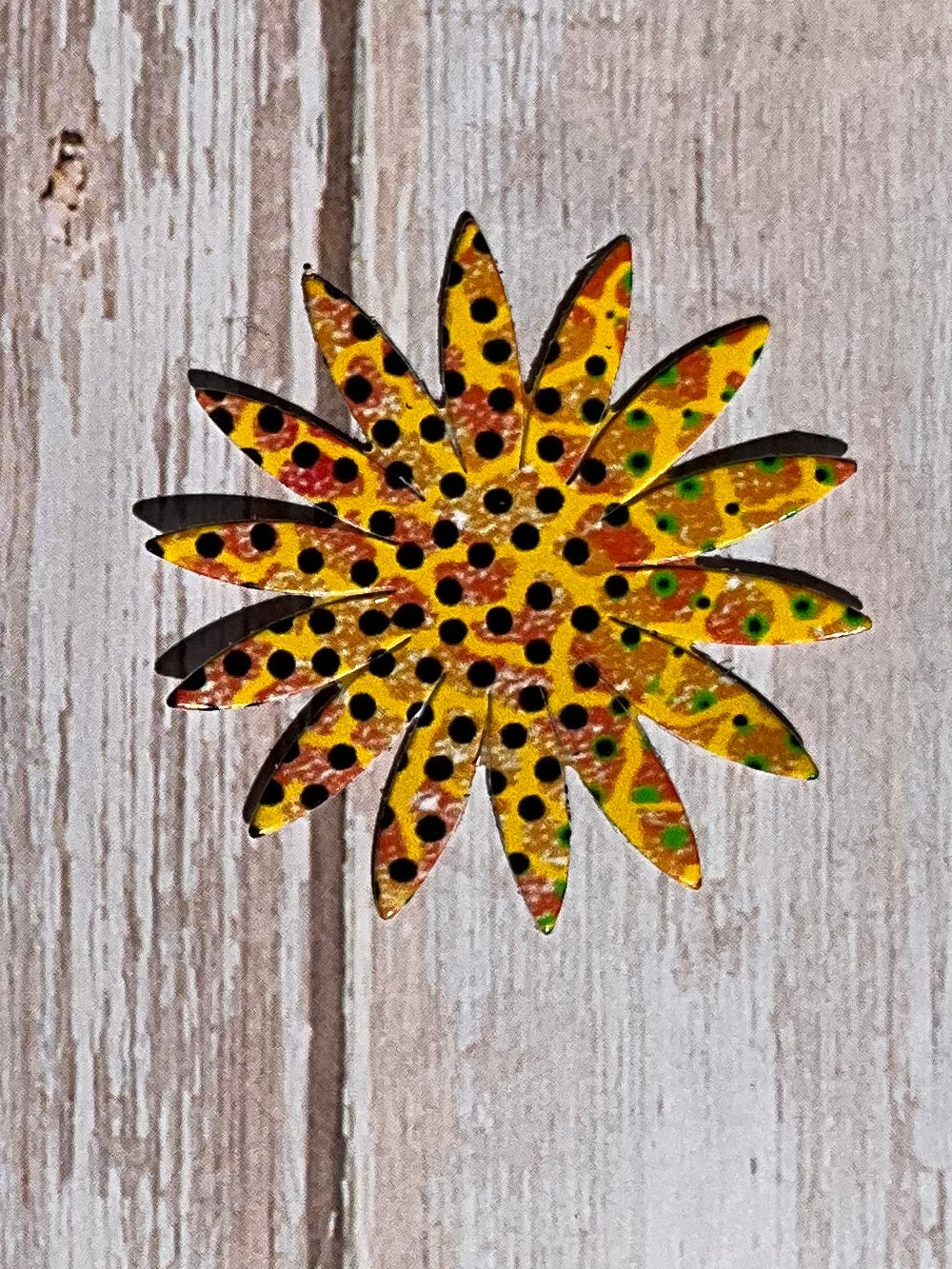 A yellow spotted sunflower shaped vinyl sticker on a wooden background