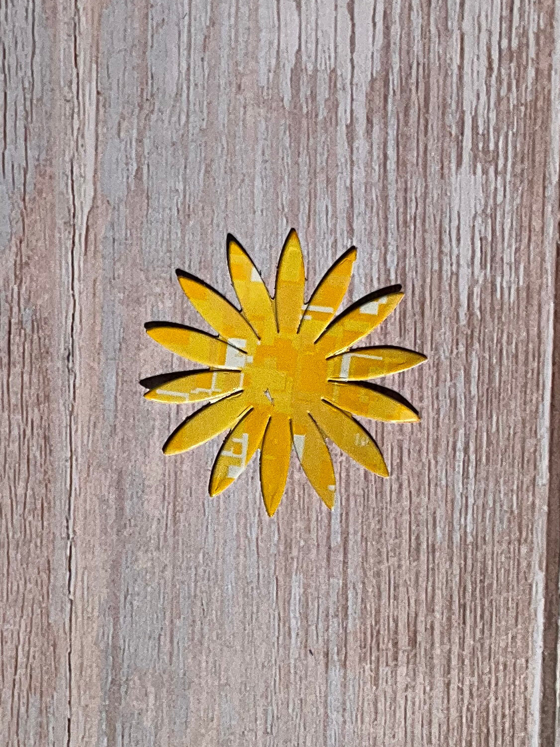 Yellow sunflower shaped vinyl sticker on a wooden table