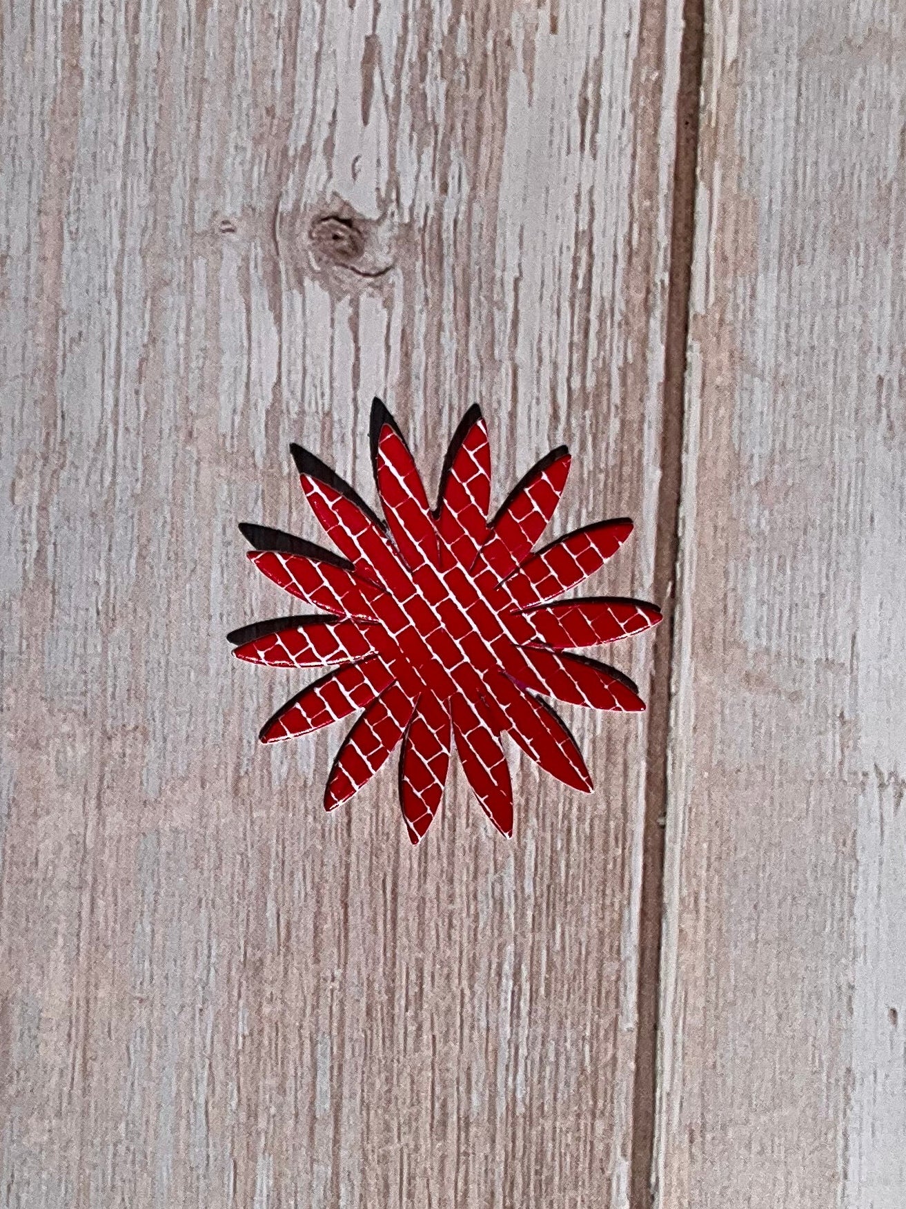 Red and white sunflower shaped vinyl sticker on a wooden background