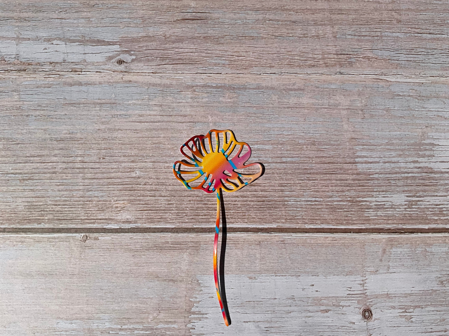 Orange and pink daisy flower sticker on a wooden surface