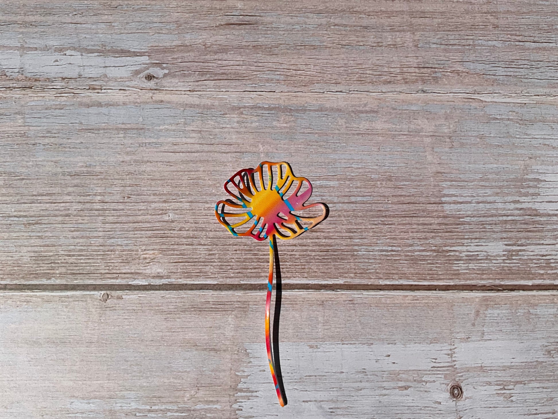 Orange and pink daisy flower sticker on a wooden surface