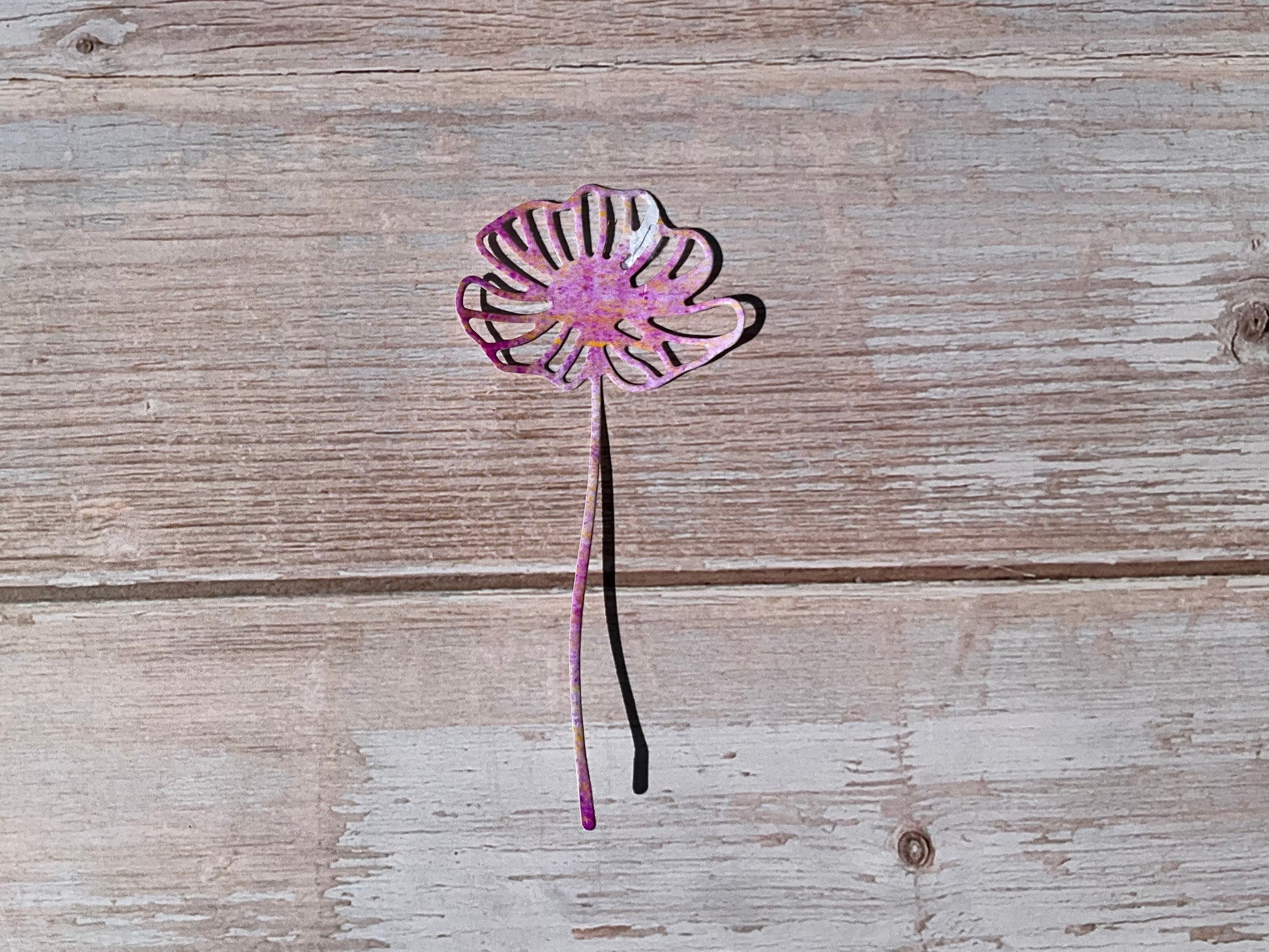 Pink daisy shaped vinyl sticker on a wooden background 