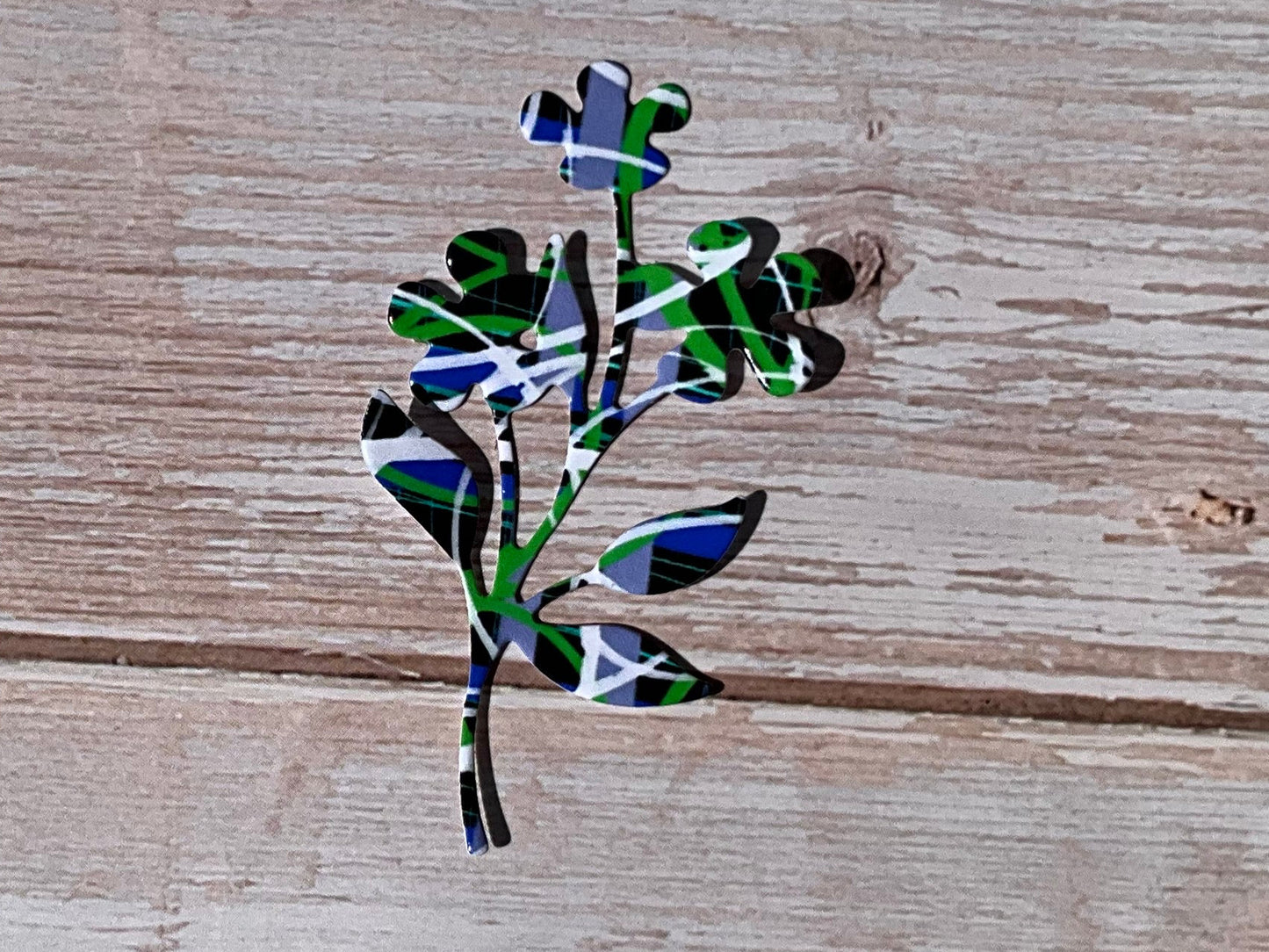 Black, blue, white and green pattern floral sticker on a light wooden background
