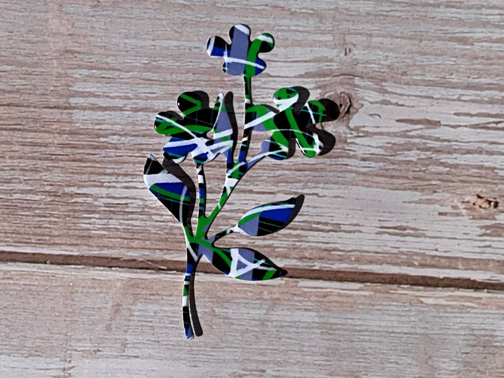 Black, blue, white and green pattern floral sticker on a light wooden background