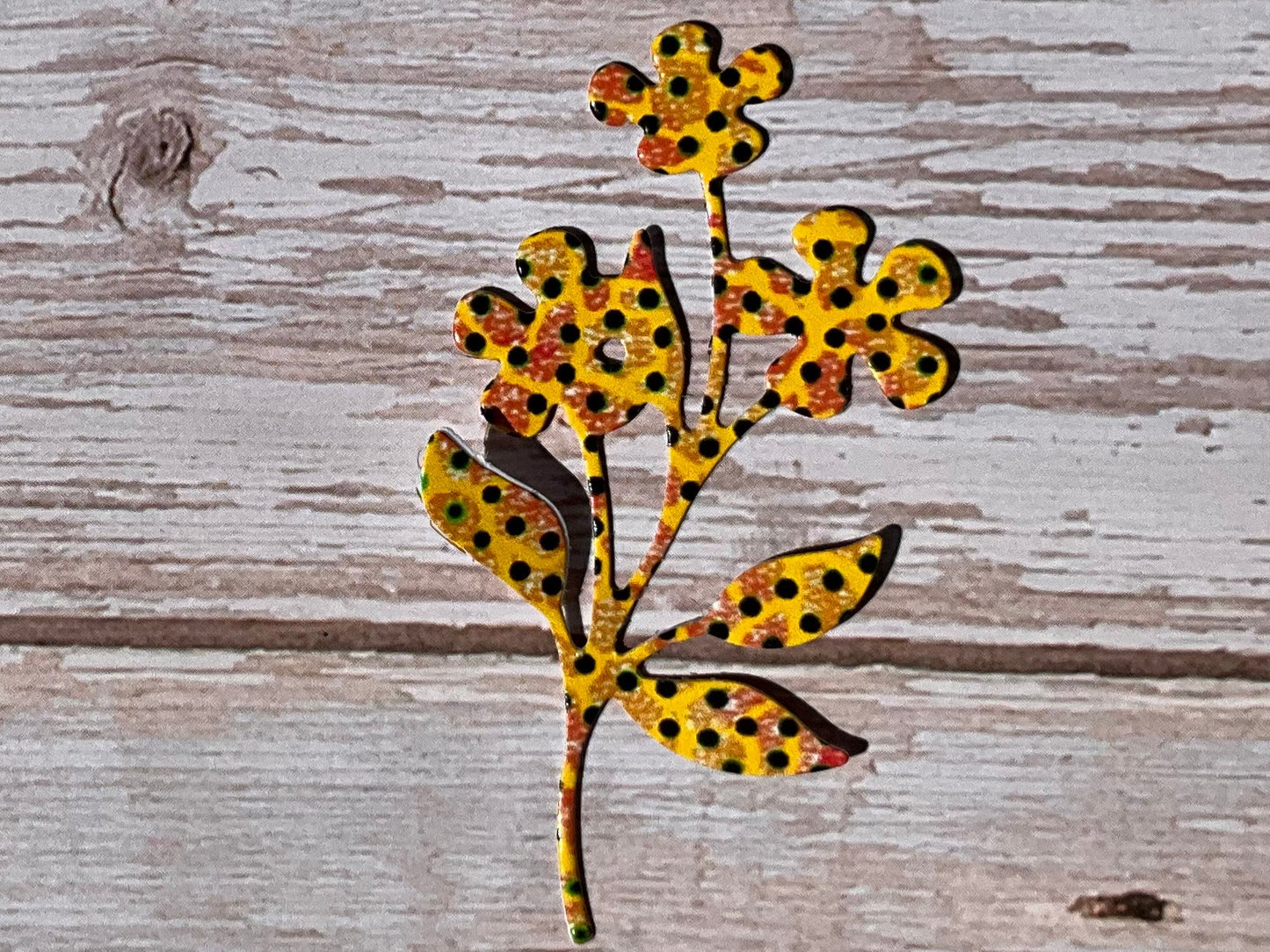 Yellow and black spotted flower sticker - vinyl sticker on wooden background. 