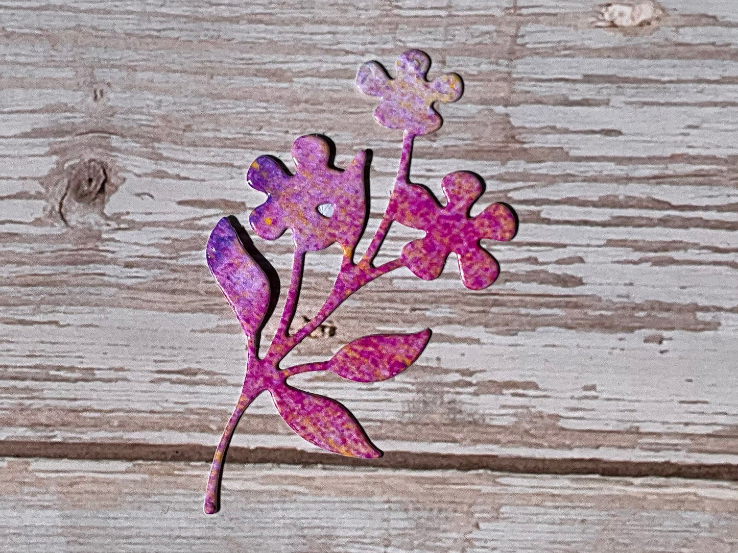 Decorative pink flower cutout sticker on a wooden surface