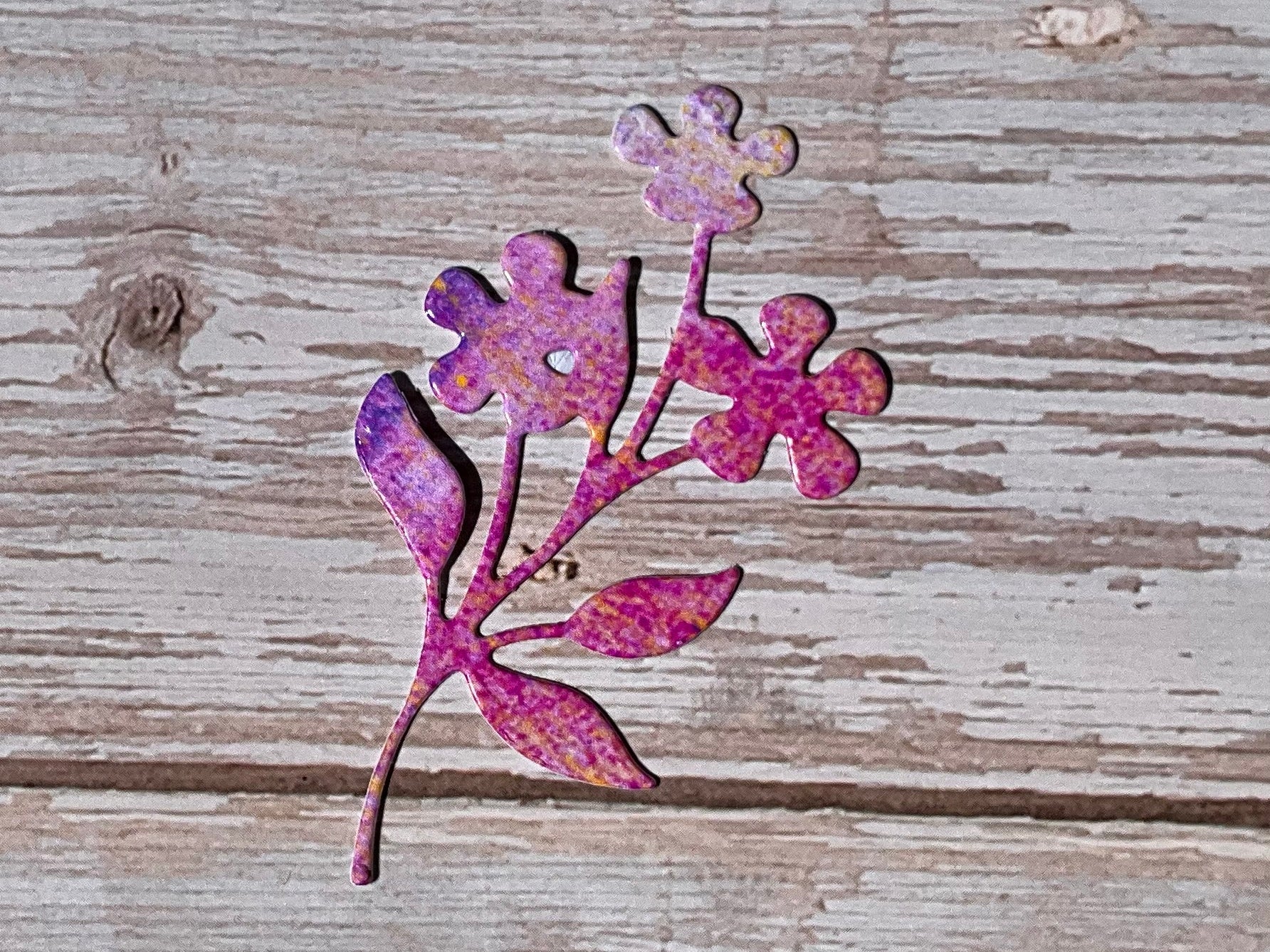 Decorative pink flower cutout sticker on a wooden surface
