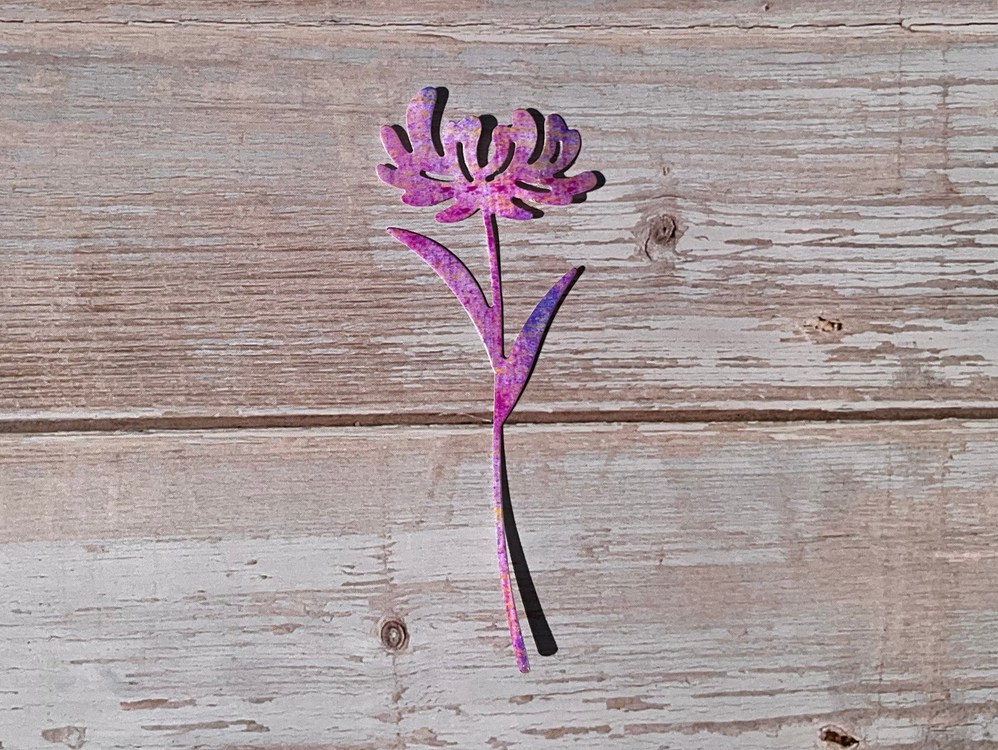 Pink and purple die cut vinyl sticker in the shape of a dandelion on a wooden background