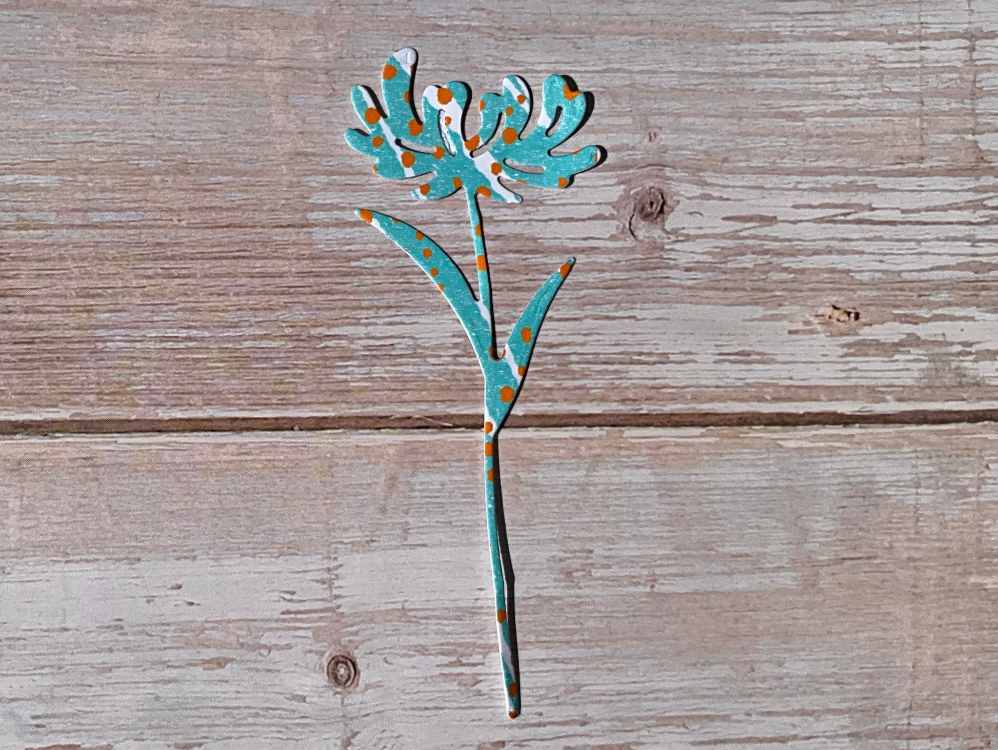 Turquoise, orange and white patterned dandelion flower vinyl sticker on a light wood background