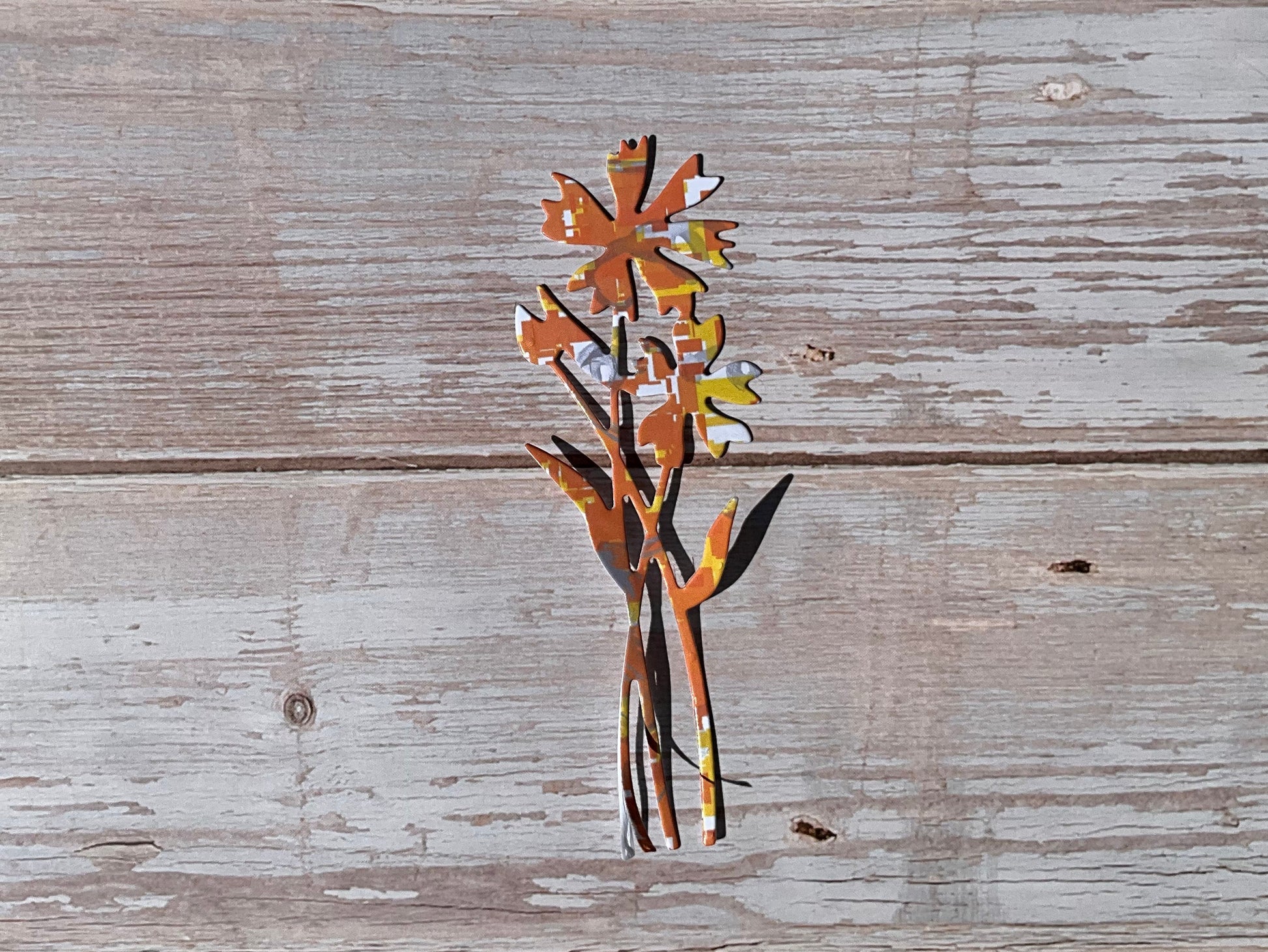Orange and yellow patterned flower die cut vinyl sticker on a wooden table
