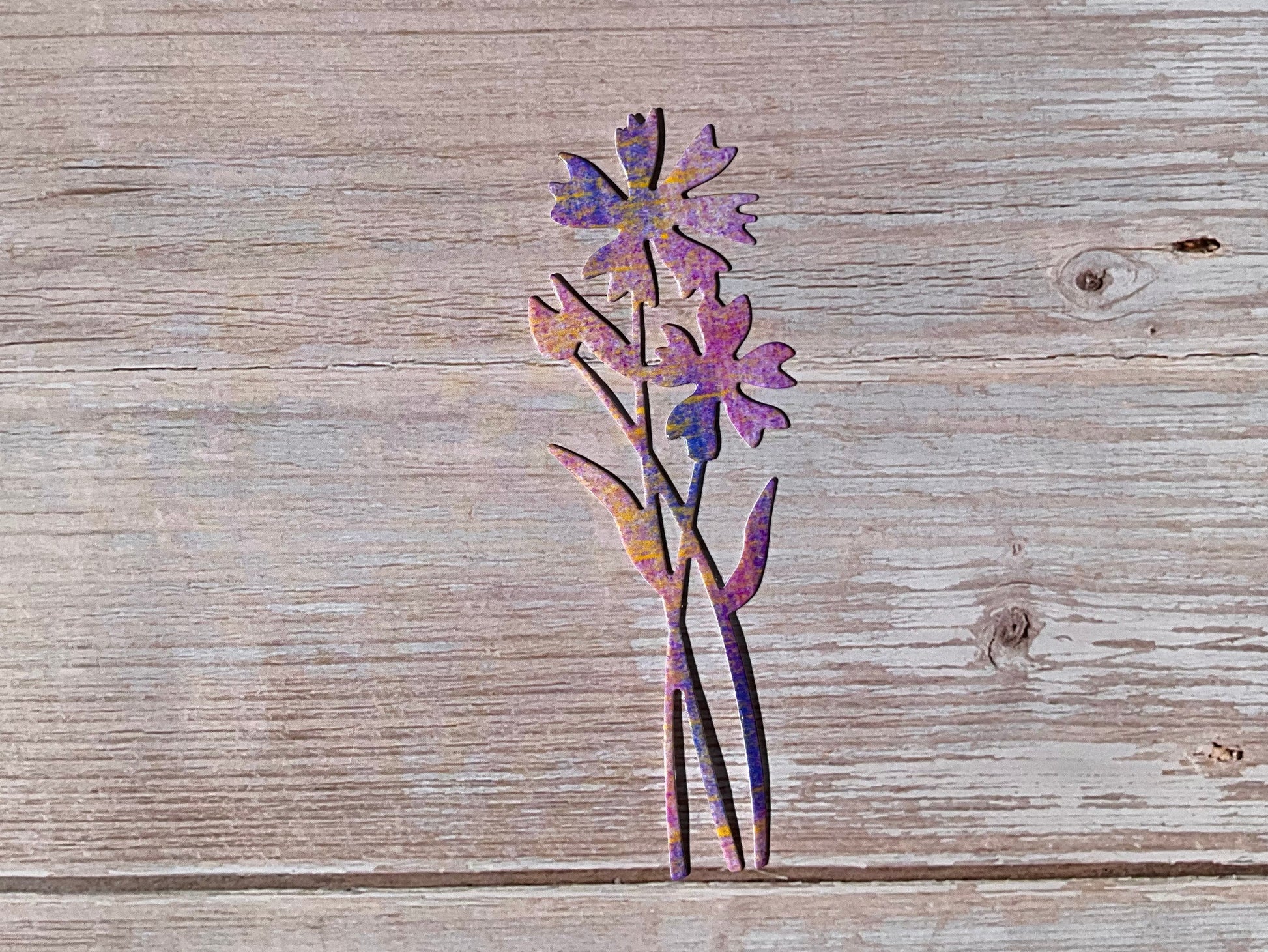 Purple and pink cornflower shaped vinyl sticker on a light wooden background
