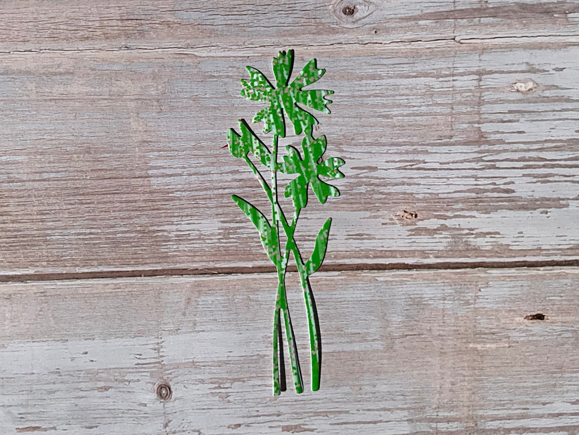 Green and white patterned flower vinyl sticker on a light wooden background