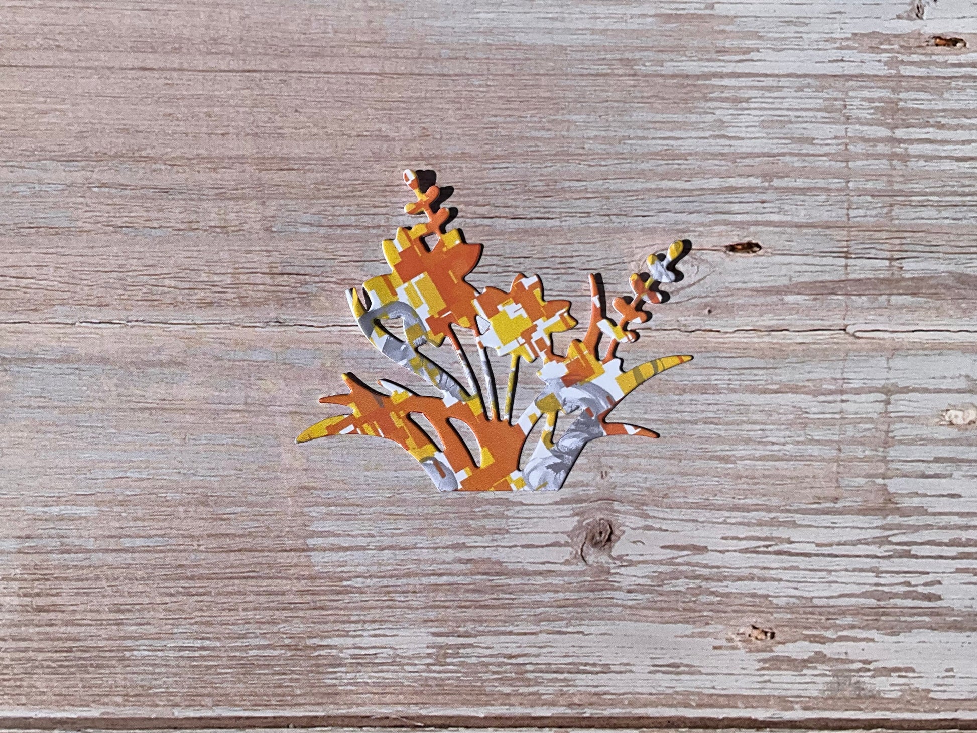 Orange yellow and grey patterned flower sticker on a wooden surface