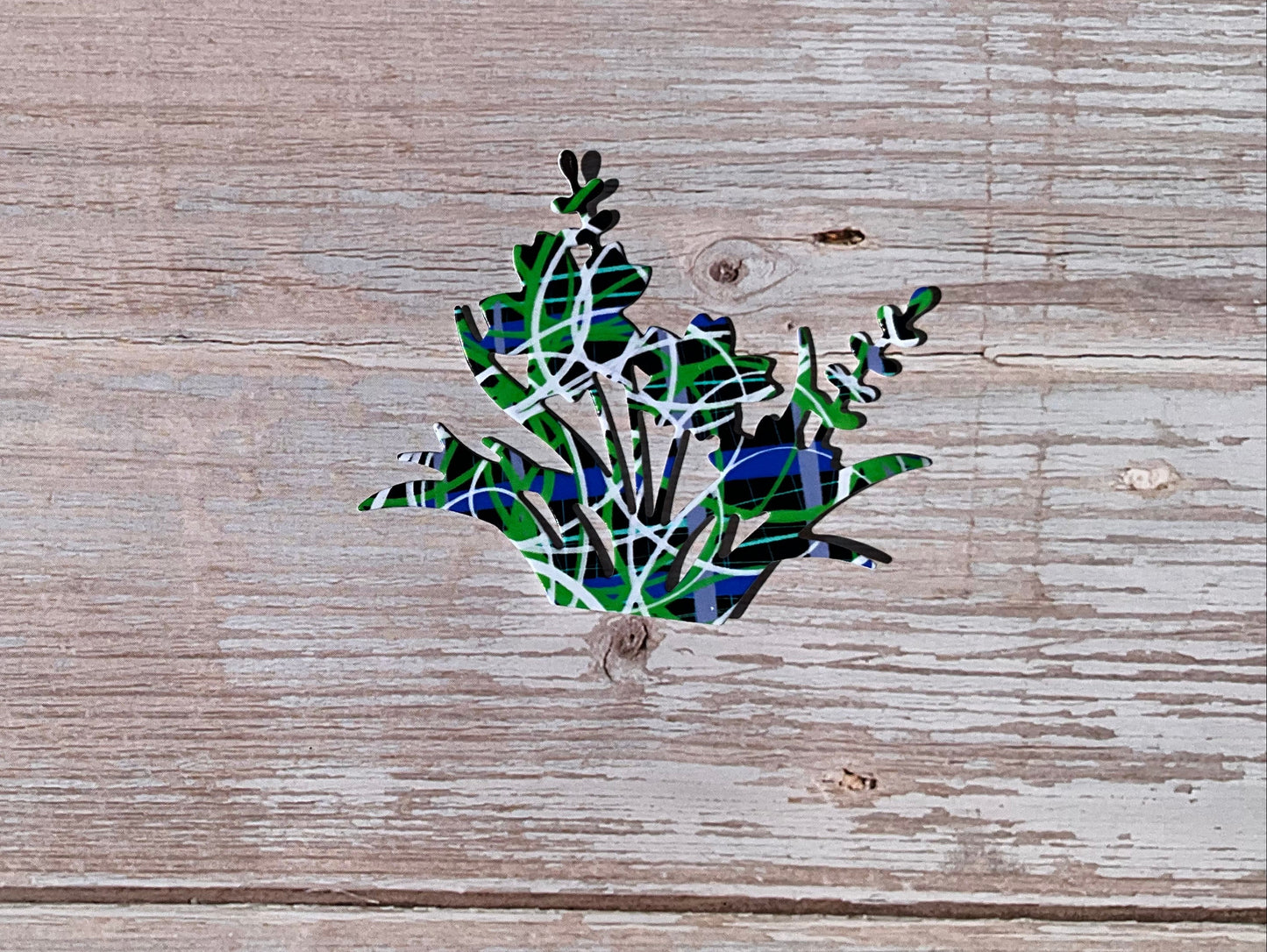 Green, blue and black vinyl floral sticker on a wooden surface