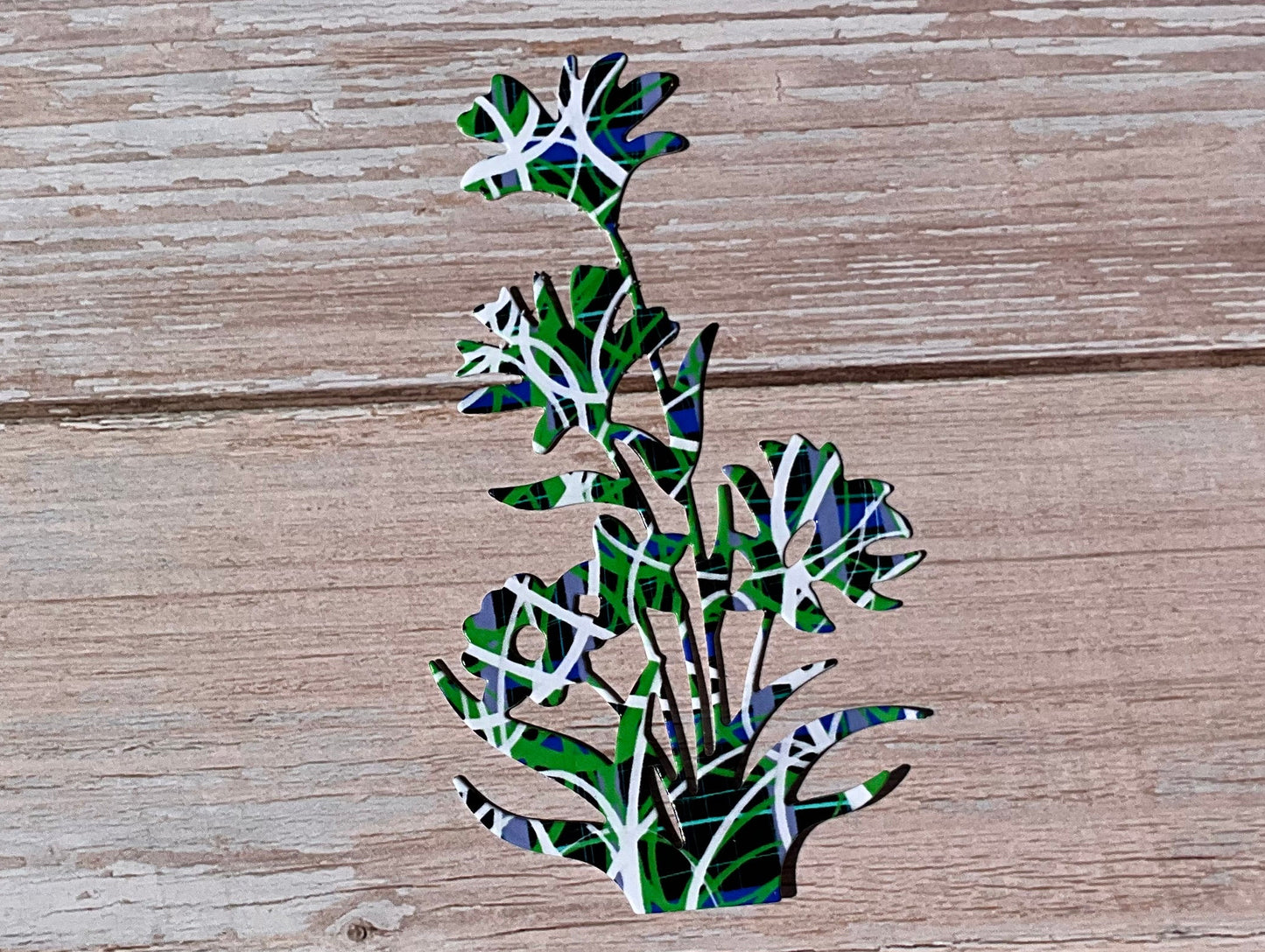 Blue, green, white and black patterned flowers sticker on a light wood panel