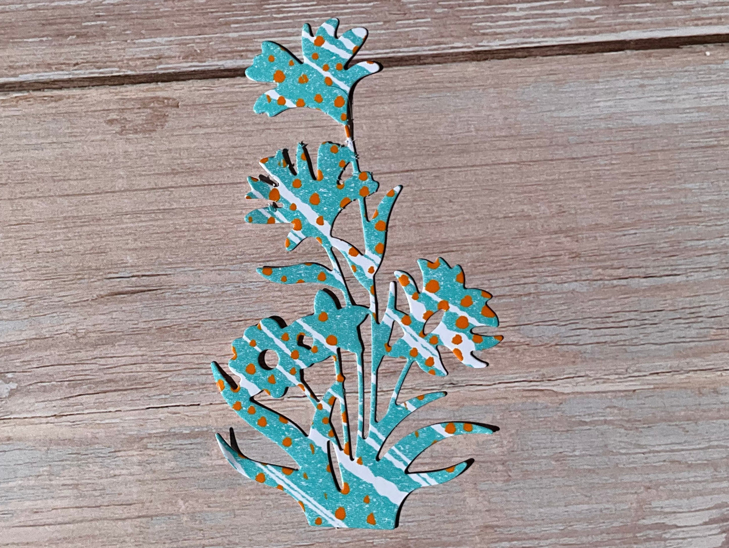 Blue and white and orange patterned flower sticker design placed on a wooden background. 