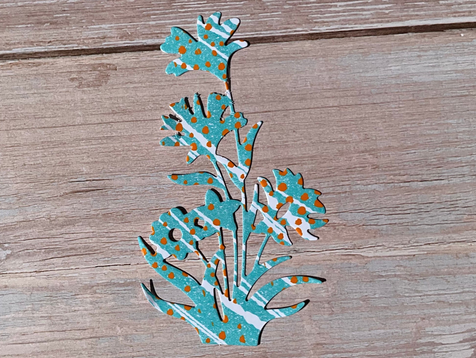 Blue and white and orange patterned flower sticker design placed on a wooden background. 