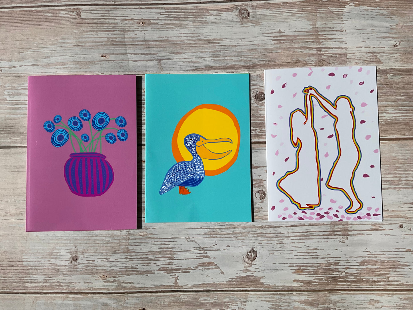 Three illustrated greeting cards on a wooden surface