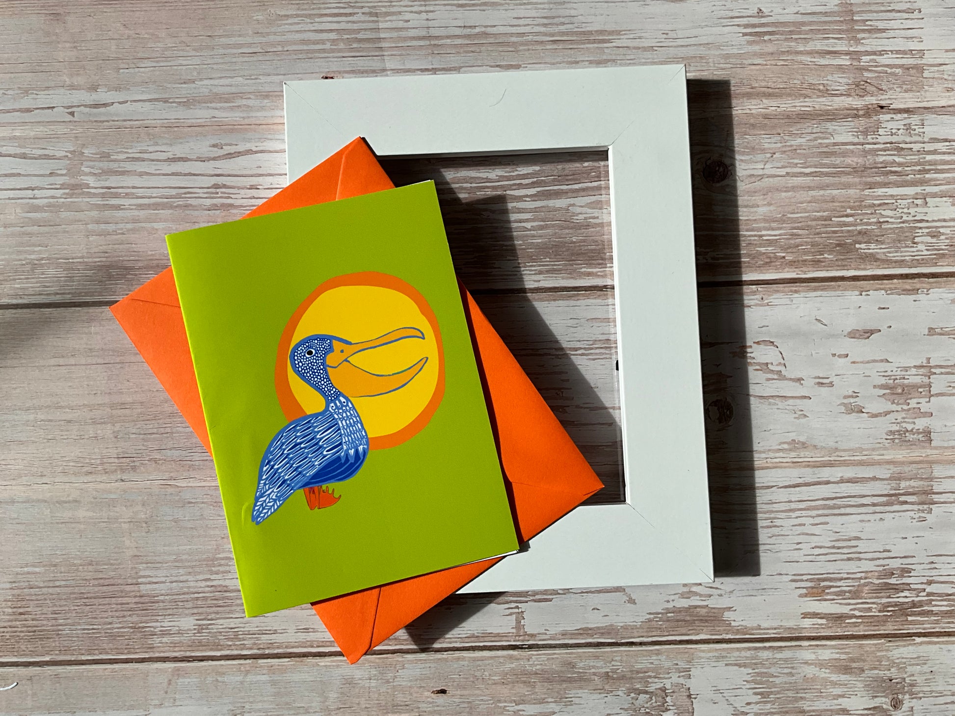 Hand-illustrated pelican greeting card with yellow sunshine and lime green background, available as a framed mini print