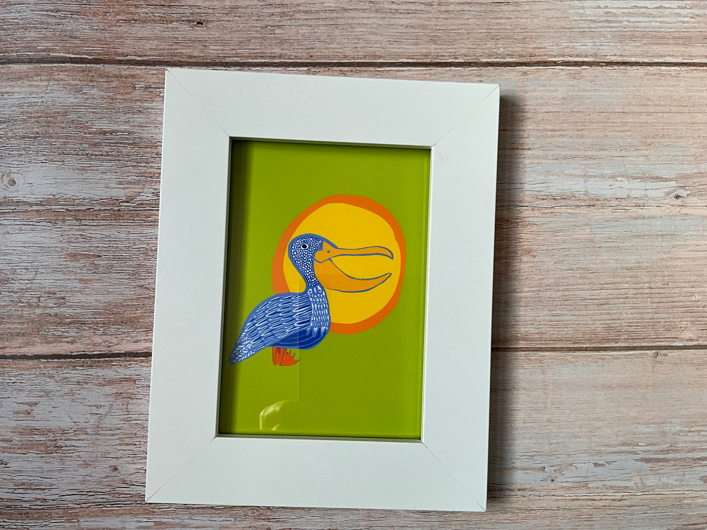 Hand-illustrated blue pelican greeting card with yellow sunshine and vibrant green background, available as a mini print