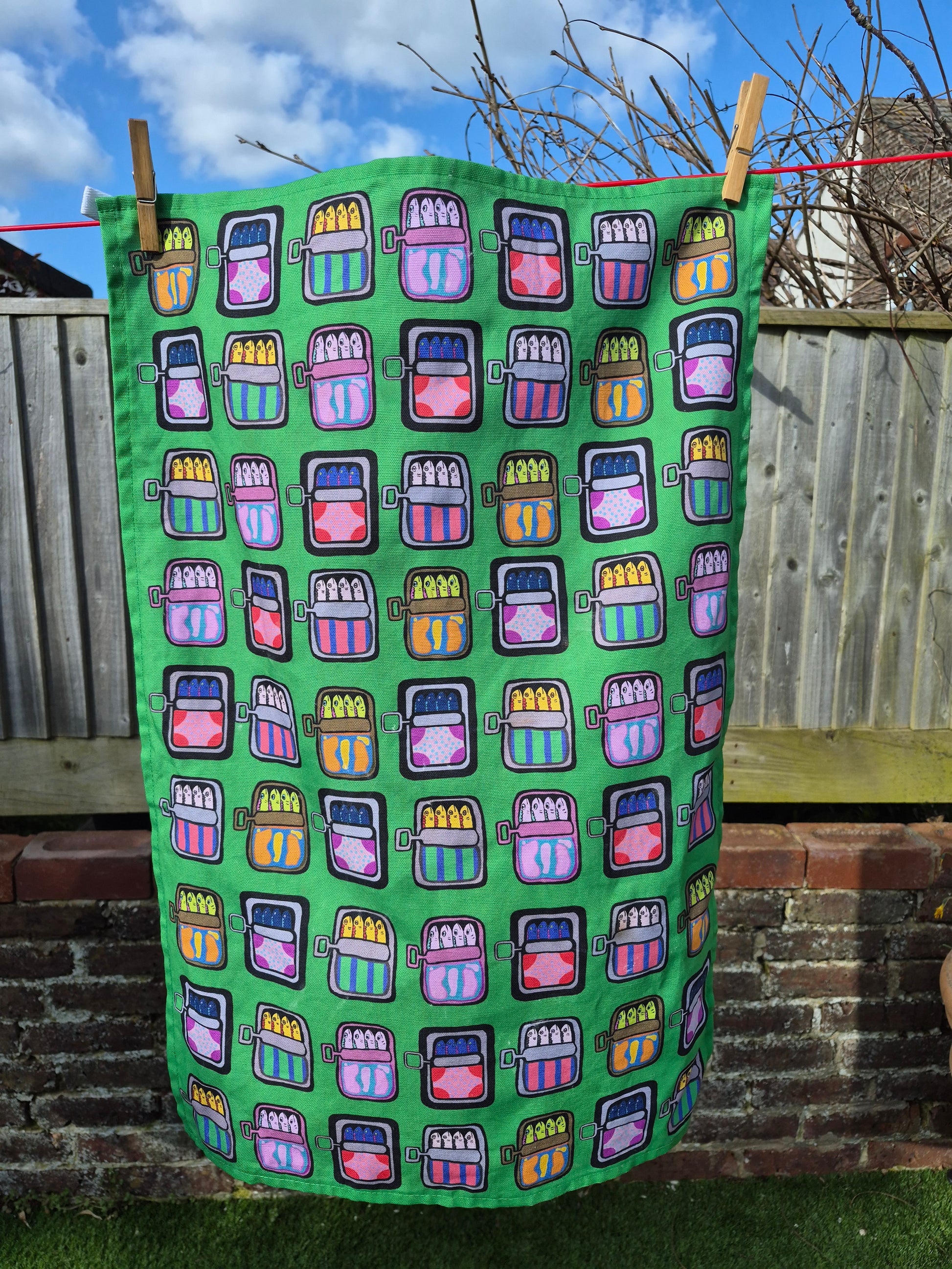 Green colourful mackerel print tea towel on washing line