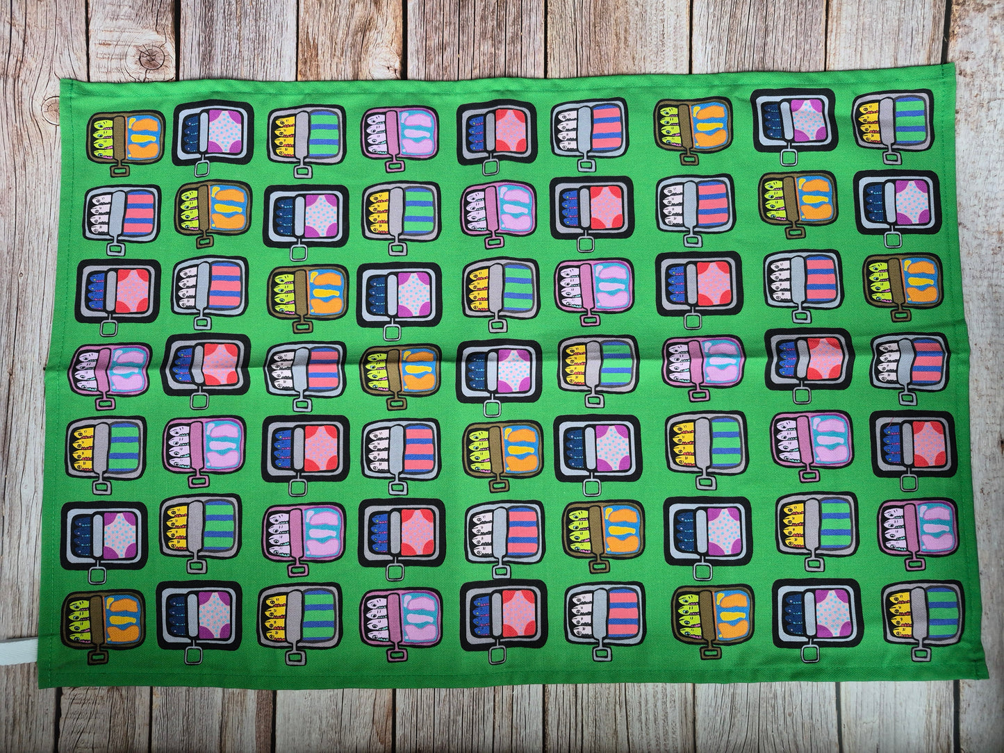 Green mackerel print tea towel on wooden background