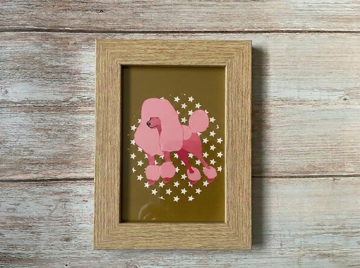 Pink poodle mini print. Hand drawn poodle and stars design on a mustard background framed in a natural wood frame