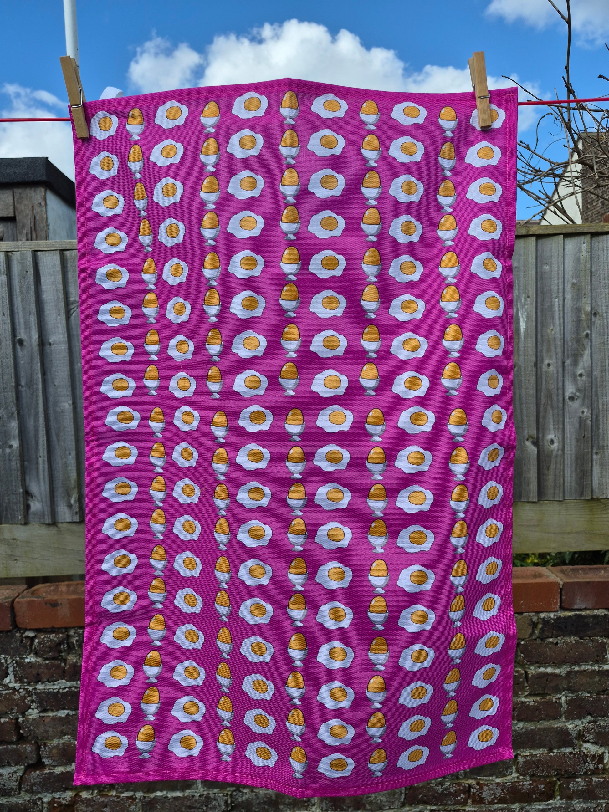 Pink egg printed tea towel on a washing line