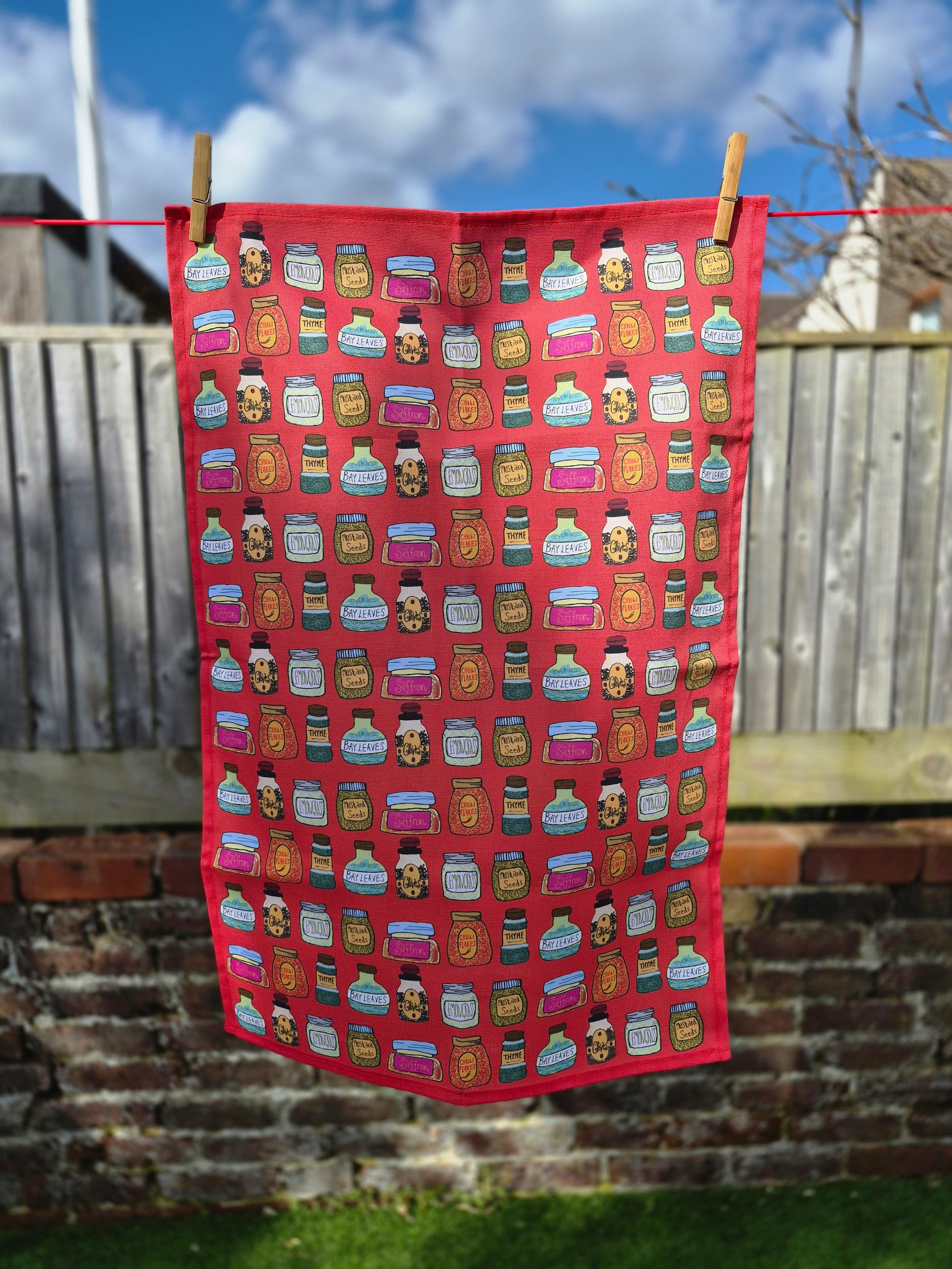 A red food themed printed tea towel hanging on a washing line