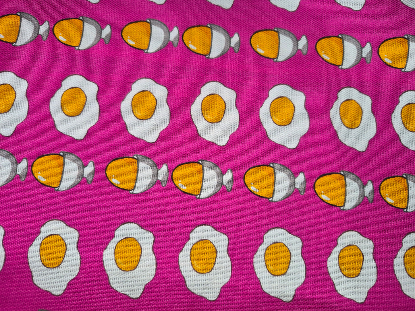close up of egg pattern on a pink tea towel