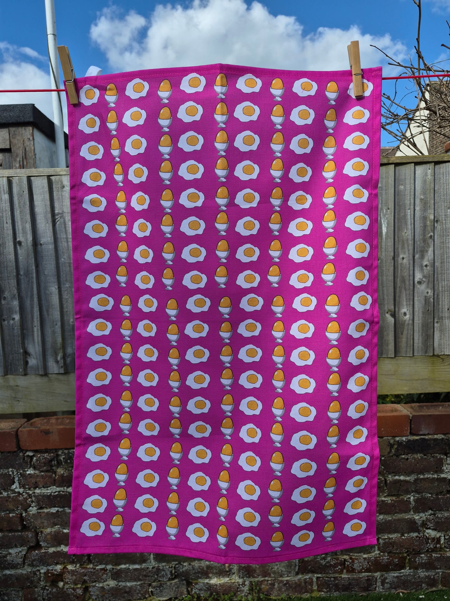 hot pink egg printed tea towel towel hanging on a washing line