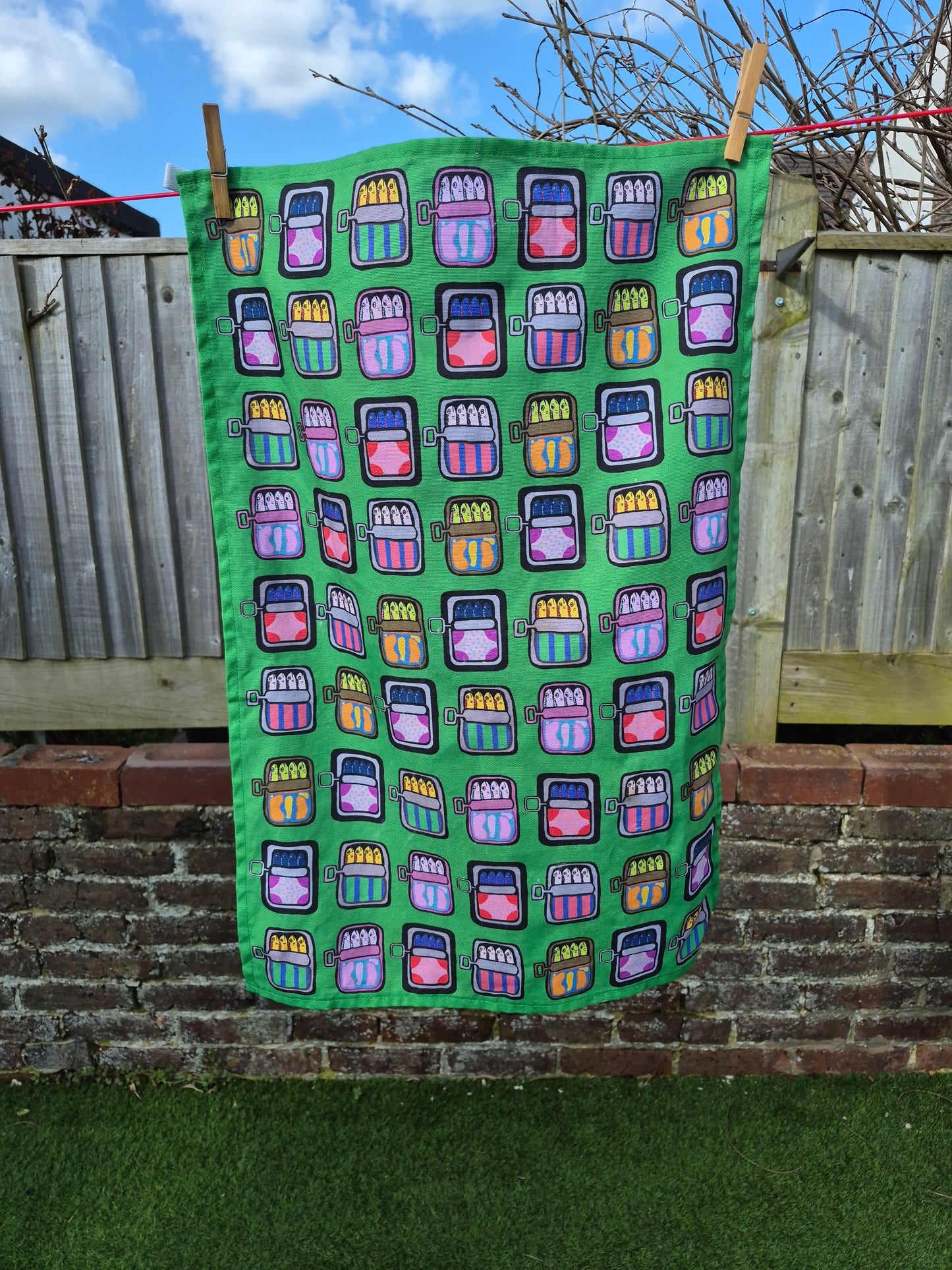Green unique and colourful mackerel print tea towel on washing line