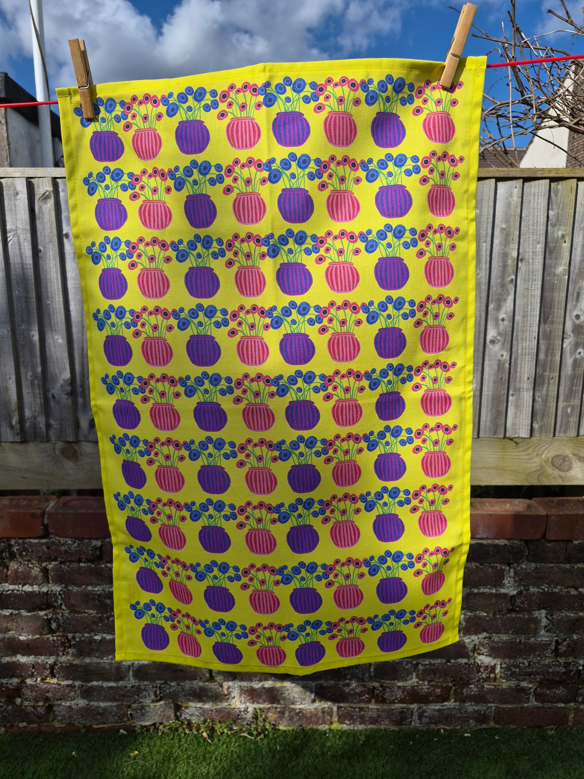 patterned yellow tea towel hanging on a washing line
